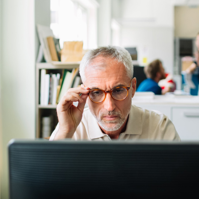 Ein Mann mit Brille, der Intelligenz und Kultiviertheit ausstrahlt, blickt selbstbewusst in die Ferne.