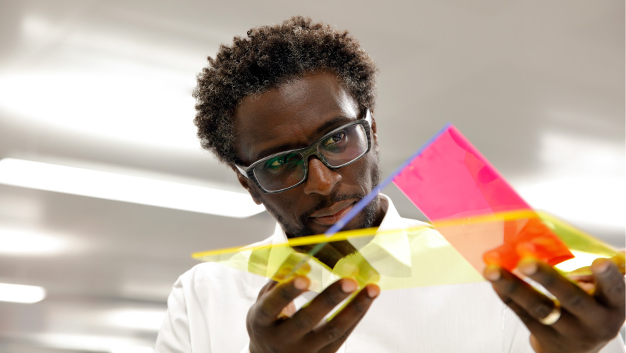 Un hombre con gafas sostiene un vibrante trozo de papel, que muestra un estallido de colores.