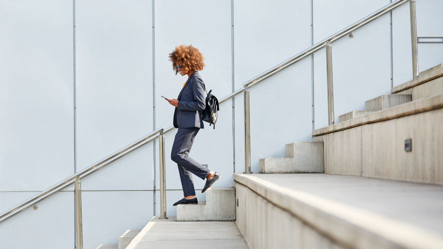 A woman in a business suit gracefully ascending a flight of stairs, exuding confidence and professionalism.