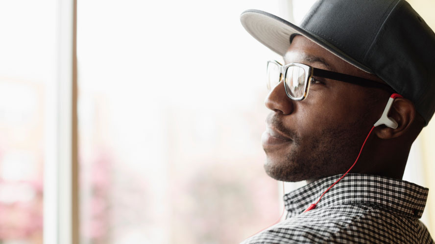 A man wearing headphones and a hat, enjoying music.