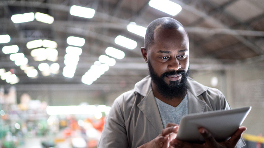 Un homme barbu absorbé par l'utilisation d'une tablette, faisant preuve d'une attention concentrée et d'un engagement technologique.