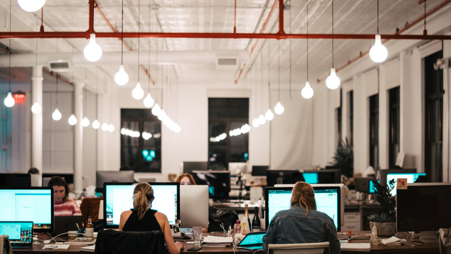 A bustling office scene with professionals diligently working on computers, fostering productivity and collaboration.