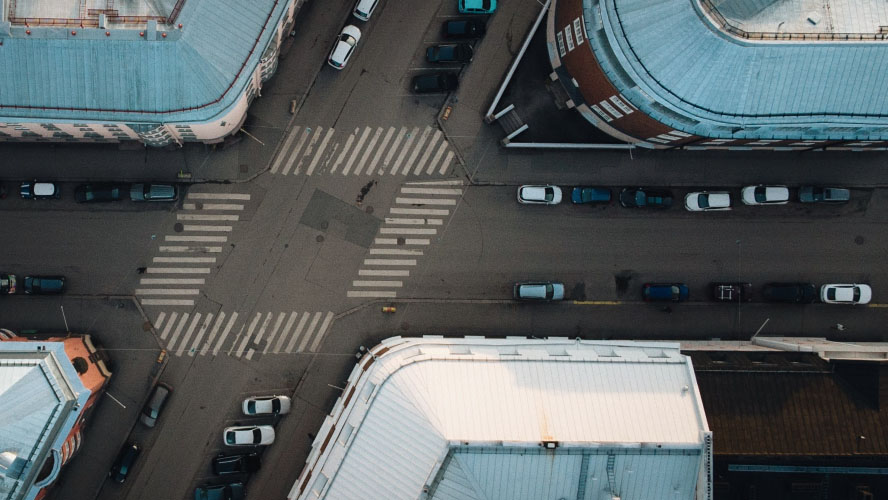 Una prospettiva aerea di un vivace paesaggio urbano, che mostra veicoli e strutture imponenti in un ambiente urbano vibrante.