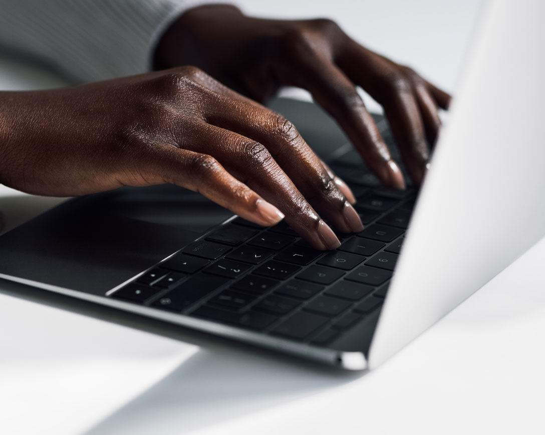 Primo piano delle mani di una donna che scrive sul computer portatile, concentrata e determinata.