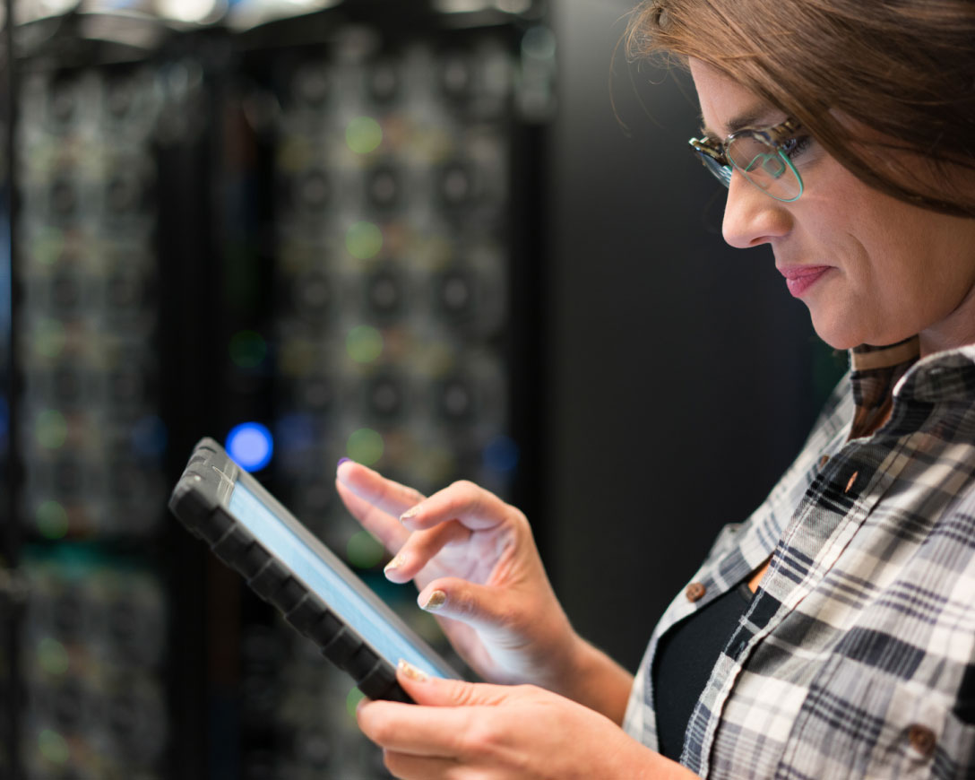 A woman in a plaid shirt and glasses using a tablet computer.