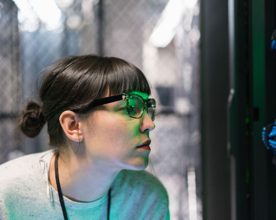 Una donna con gli occhiali è concentrata sullo schermo di un computer, assorta nel suo lavoro.