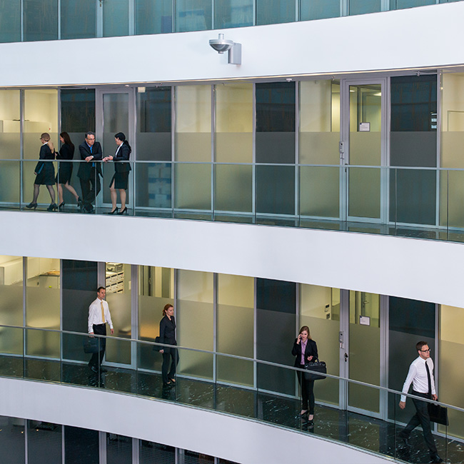 View from the atrium of an office building, looking at businesspeople walking the halls of 2 different floors