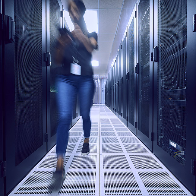 Une femme au mouvement flou qui marche rapidement dans une salle de serveurs.