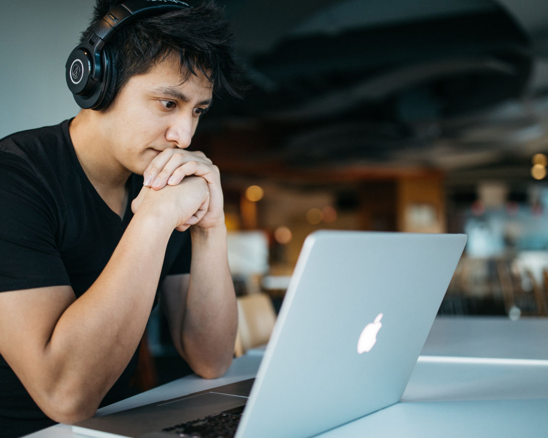 Un uomo che lavora al suo computer portatile con le cuffie.