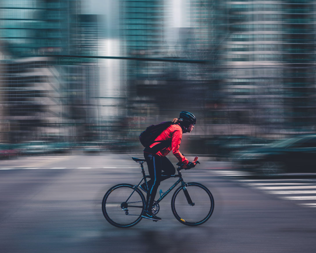 Un ciclista che attraversa in bicicletta una strada trafficata della città.