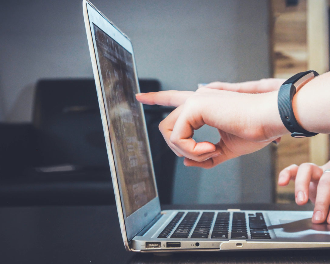 A person pointing at a laptop screen, working on a project.