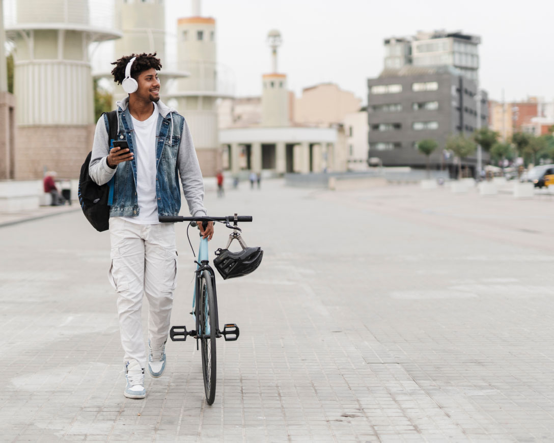 Un ciclista con auriculares pasea por la calle, disfrutando de la música mientras camina con su bicicleta.