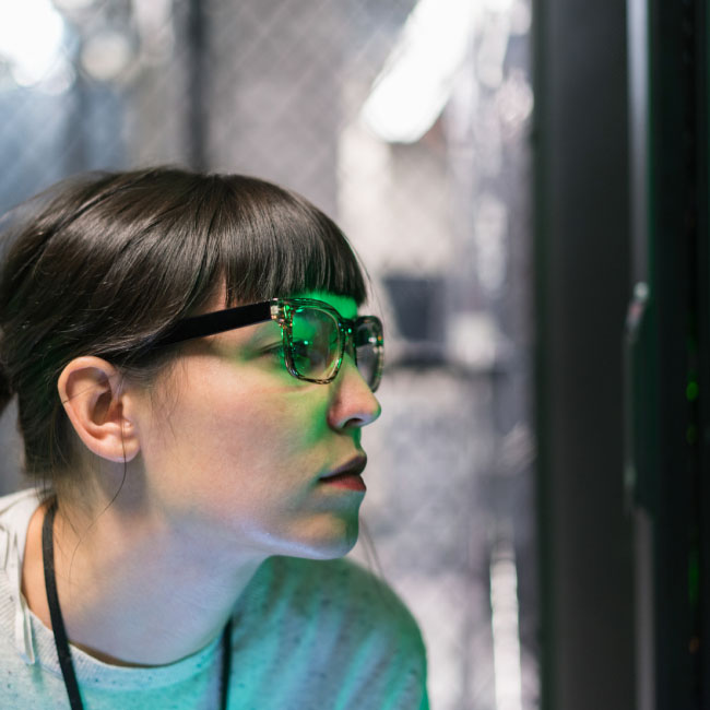 Una mujer con gafas se concentra en la pantalla de un ordenador, absorta en su trabajo.