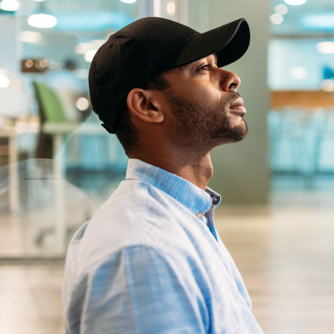 A man wearing a baseball cap gazes upwards, captivated by the sky's allure, lost in wonder and curiosity.