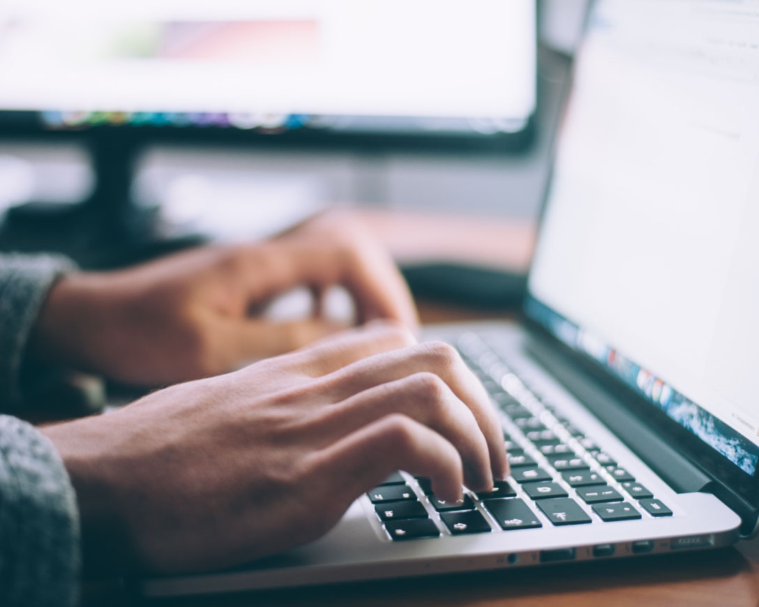 A person focused on a laptop, typing intently.